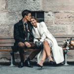 Brautpaar sitzt auf einer alten Bank.