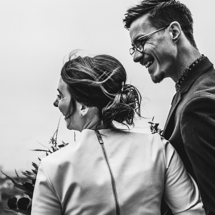 Schwarz-Weiß-Fotografie Hochzeitspaar. Beide seitlich zu sehen. Lachen herzlich