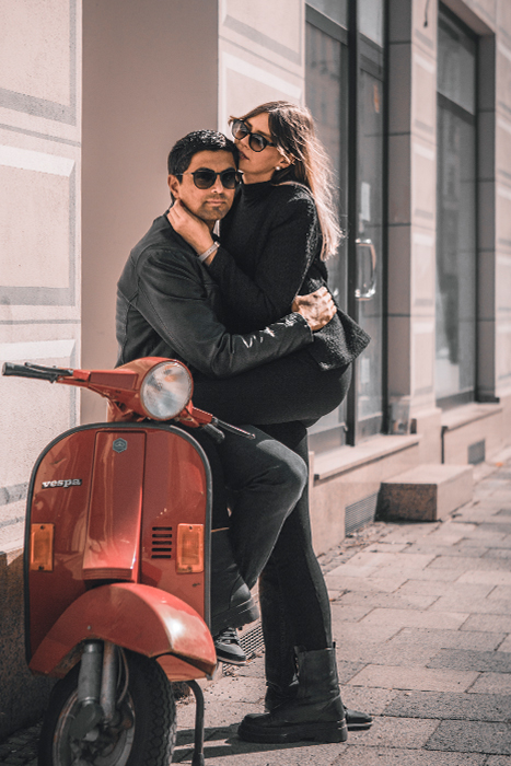 Stylisches Paar in schwarz gekleidet posiert auf Vespa