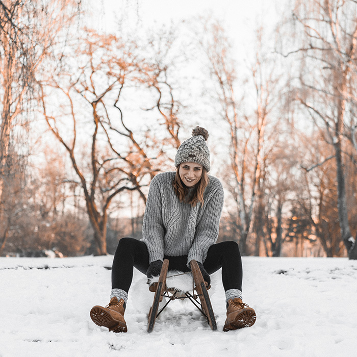 Junge Frau rodelt durch Winterlandschaft