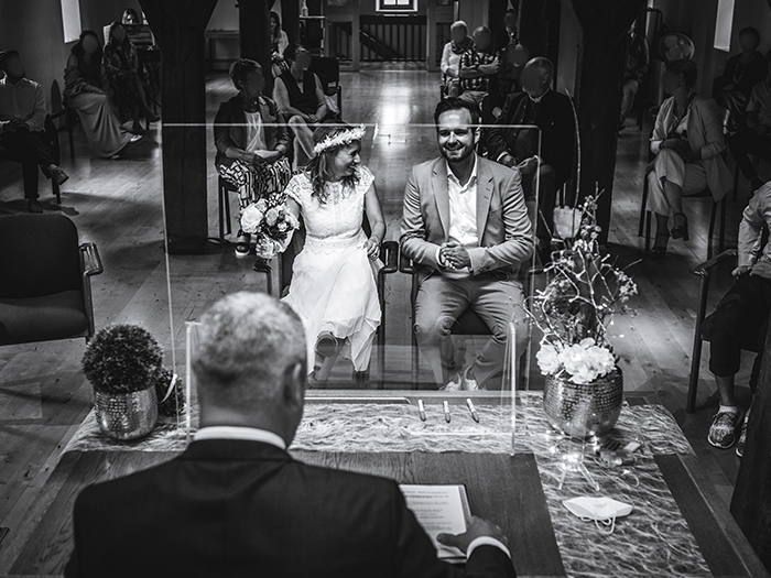 Hochzeitspaar sitzt vor Standesbeamten. Schwarz-weiß-Foto