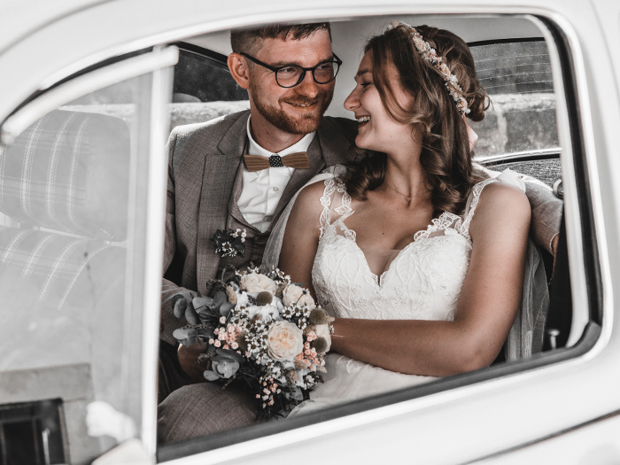 Brautpaar sitzt turtelnd im Hochzeitsauto