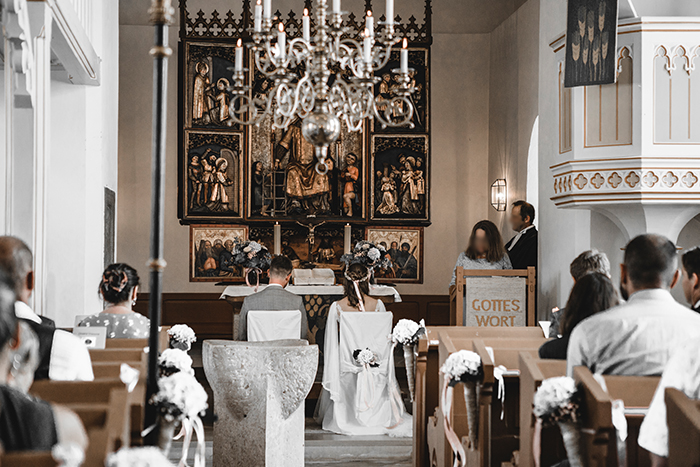 Brautpaar sitzt vor Altar bei Trauung