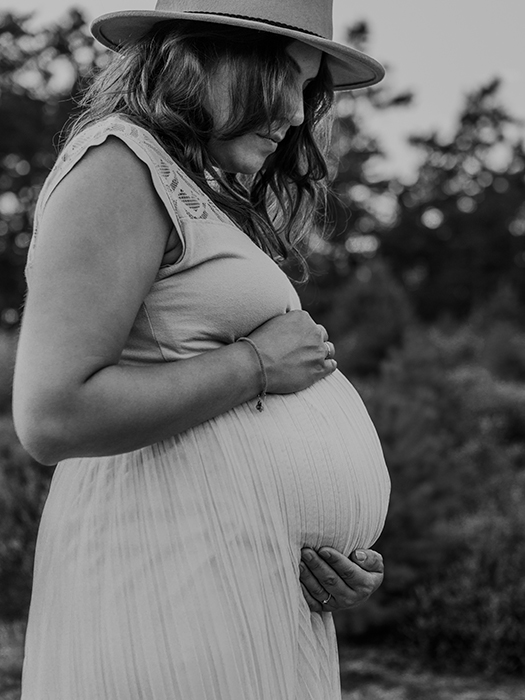 Babybauchshooting. Werdende Mami hält ihren Bauch von oben und unten fest. Schwarzweißbild