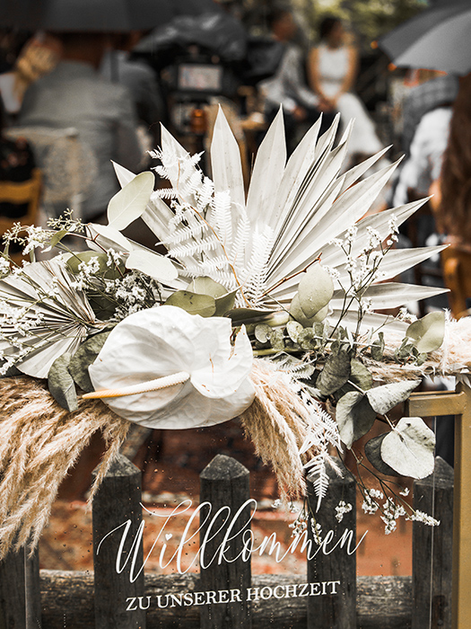 Willkommensschild zur Hochzeit mit Blumenschmuck in weiß