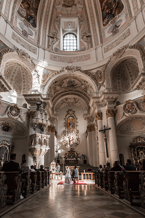 Brautpaar steht vor dem Traualtar in einer eindrucksvollen Kirche