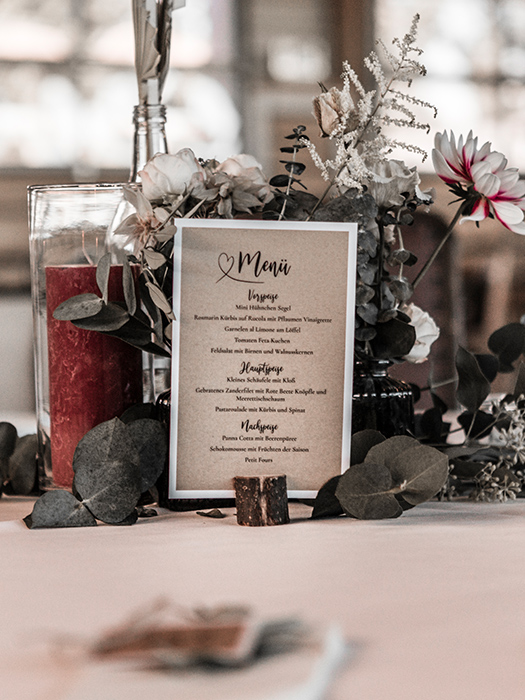 Hochzeitsmenükarte mit Blumendeko im Hinergrund