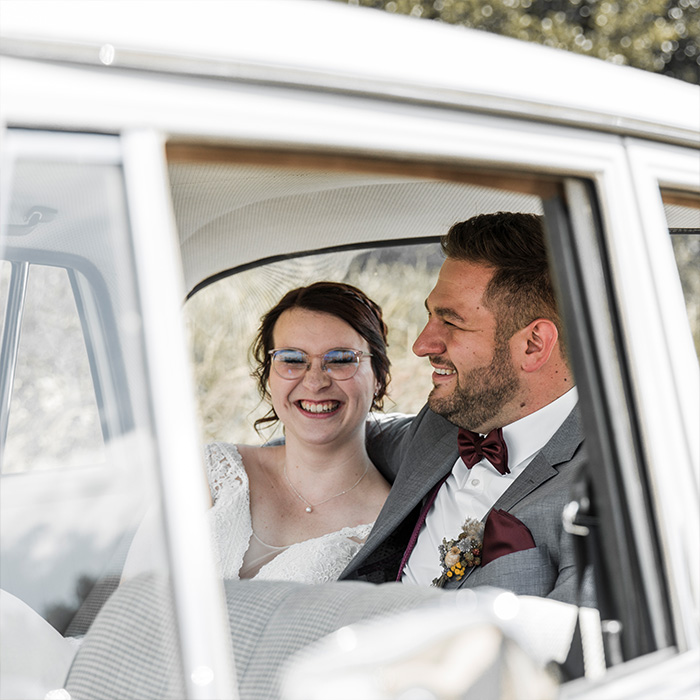 Brautpaar im Hochzeitsauto lacht herzlich