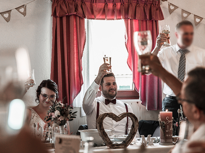 Vater des Bräutigams bringt Toast auf das Brautpaar. Alle heben Gläser