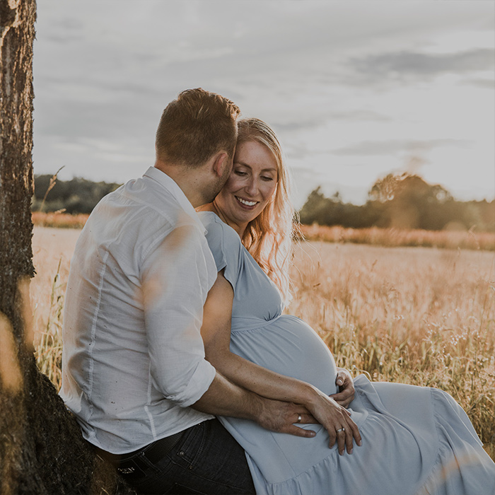 Babybauchshooting: Paar schmust unter einem Baum