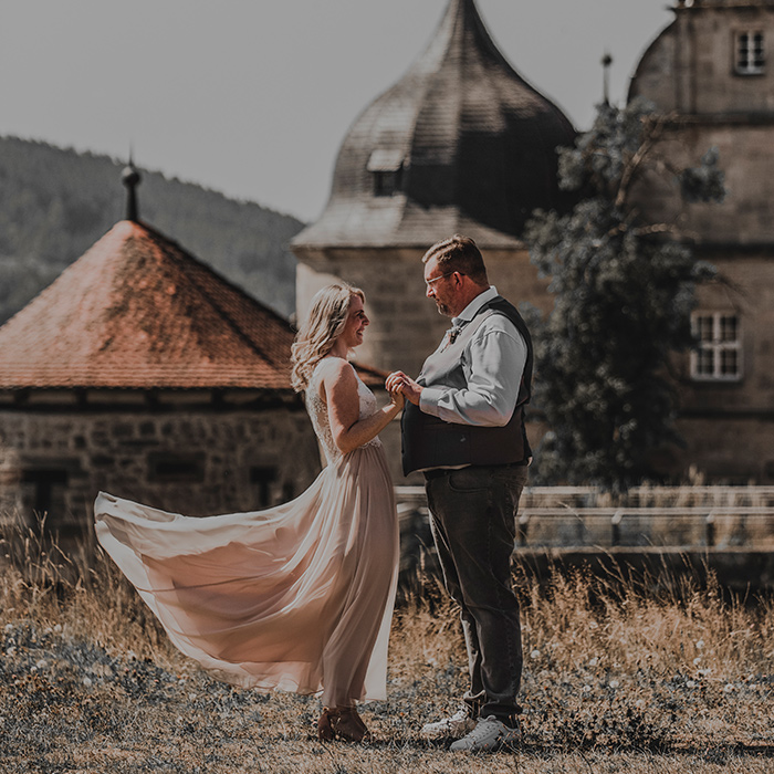 Brautpaar vor Festung. Ihr Kleid weht im Wind