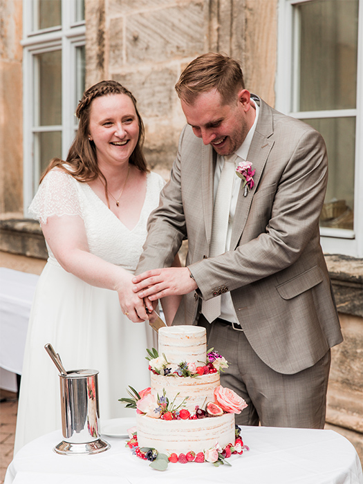 Brautpaar schneidet gemeinsam Hochzeitstorte an