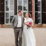 Brautpaar steht vor einem Schloss