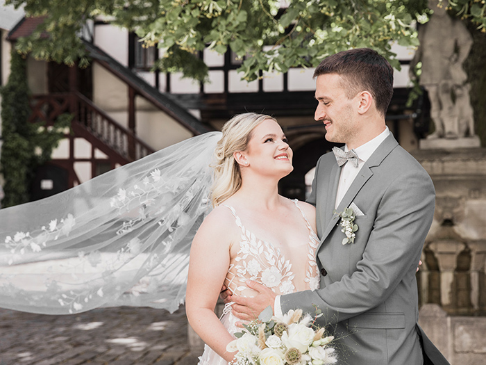 Brautpaar schaut sich verliebt an. Ihr Schleier weht im Wind