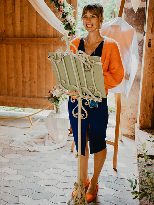 Lachende Traurednerin vor Rednerpult in Trauscheune