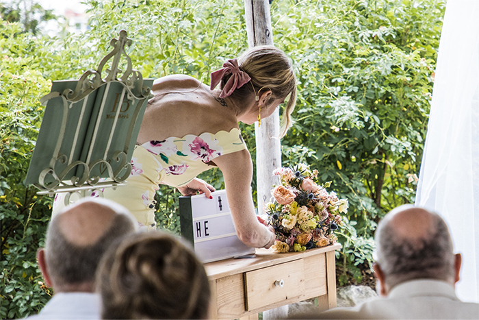 Freie Traurednerin setzt das Wort Heiraten in einem Leuchtkasten während der Trauung